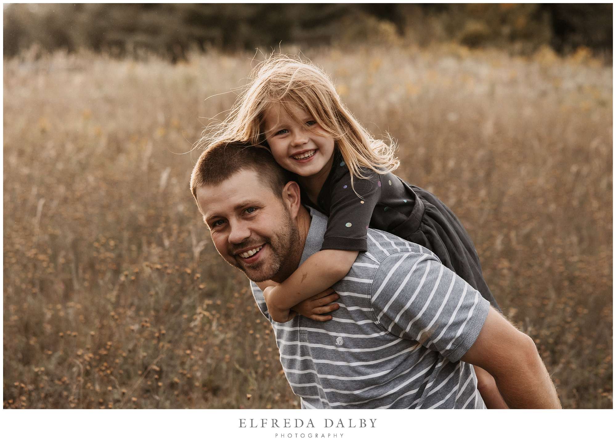 Dad piggy back his little girl in a field